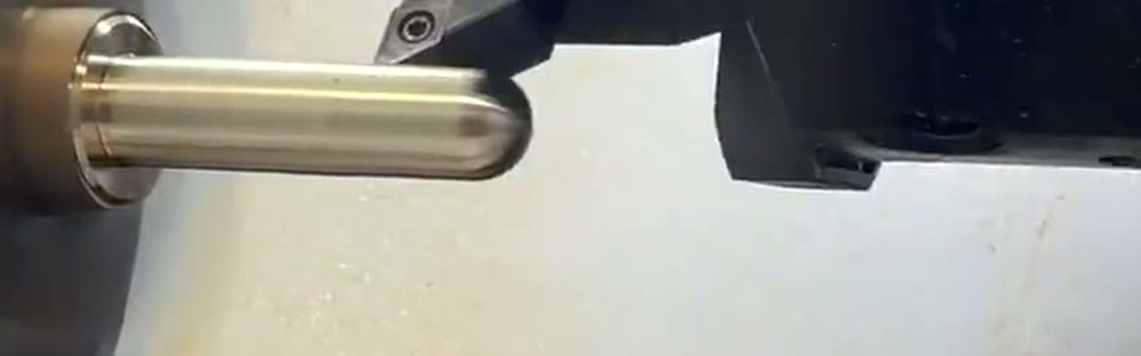 CNC lathe turning a bright metal workpiece, cutting tool engaged