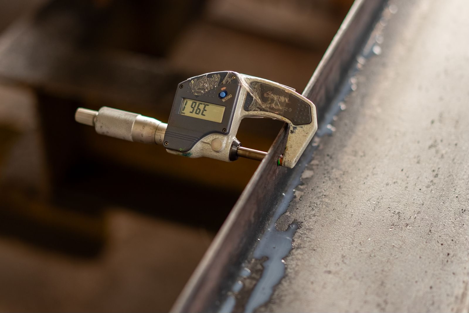 Digital micrometer measuring a steel edge at the shop-floor QC bench